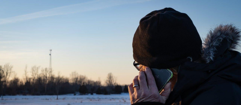 Man on cell phone, winter sunset in background