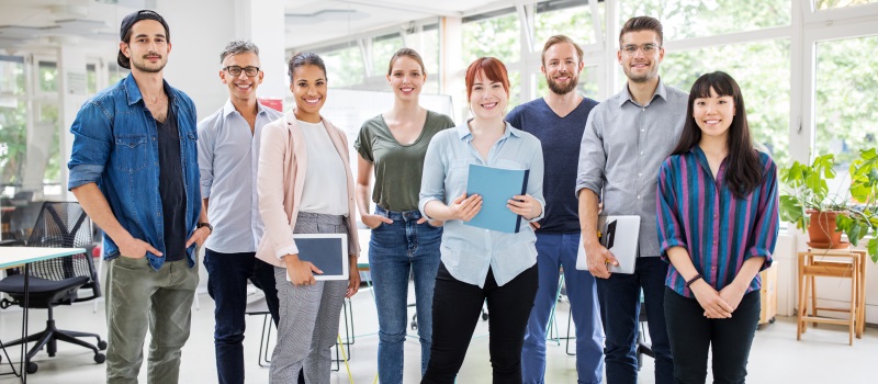 group of people smiling holding laptops and notebooks